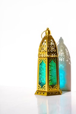 Beyaz arka planda güneş ışığının gölgesi olan altın fener. 