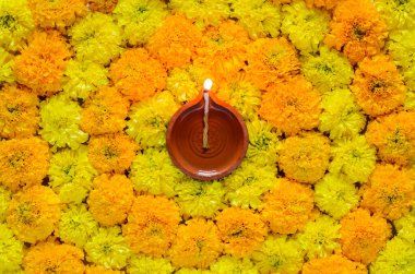 Decorative marigold flower rangoli for Diwali festival with clay diya lamp lit with blurred focus flame.