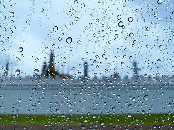 Selective focus at water drop on car glass when raining in monsoon season with blurred background.