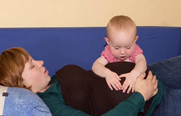 Baby girl investing her pregnant mothers belly — Stock Photo, Image