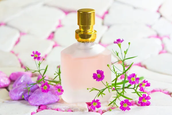 Pretty frosted bottle of perfume with flowers — Stock Photo, Image