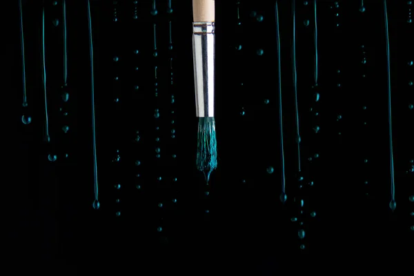 yeşil boya siyah arka planda fırçanın etrafına damlıyor.