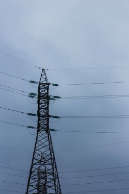 Bulutlu gökyüzünün arka planında elektrik hatları.