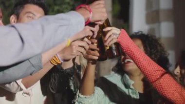 Çeşitli insanlar çatırdıyor ve bira şişelerini kaldırıyor.