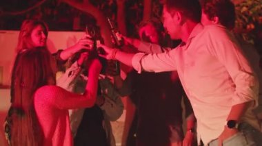 Bir grup arkadaş arka bahçede dikiliyor, bira şişelerini tıkırdatıyorlar.