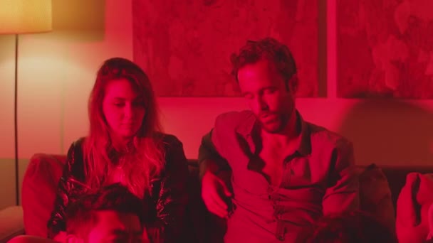 Amigos sentados no quarto escuro com luz vermelha na festa em casa — Vídeo de Stock