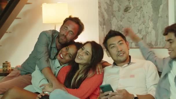 Slider shot van gelukkige vrienden zitten op de bank en knuffelen — Stockvideo