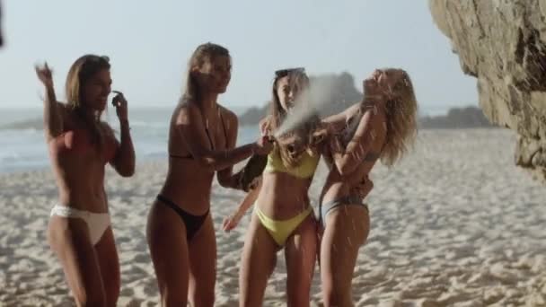 Vista frontal de chicas felices haciendo estallar champán en la playa de arena — Vídeo de stock