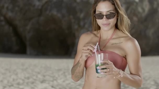 Movimento vertical da mulher de pé e beber coquetel na praia — Vídeo de Stock