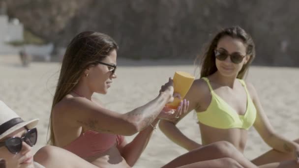 ビーチに座って日焼け止めを適用する女の子のスローモーション — ストック動画