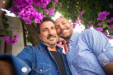 Gülümseyen eşcinsel çift romantik yolculukta selfie çekiyor.