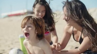 Mutlu ablalar, kumsalda kardeşini gılıyor. 