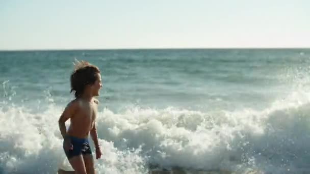 海岸線を走る幸せな白人の少年の側面図 — ストック動画