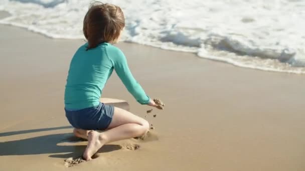 Largo tiro de feliz poco caucásico chico salpicando en el mar — Vídeos de Stock