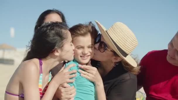 Vista frontale della famiglia felice seduta insieme sulla spiaggia e baciare — Video Stock