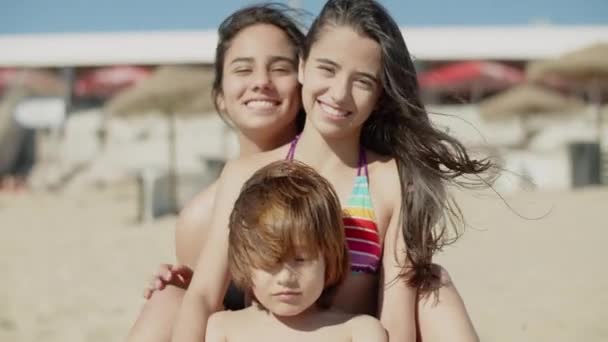 Vista frontale dei bambini felici seduti insieme sulla spiaggia e abbracciati — Video Stock