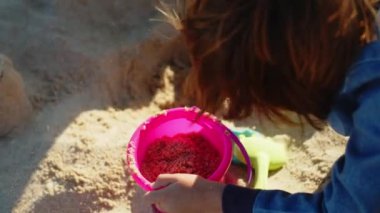 Baba ve oğlunun sahildeki kovada kum topladığı yakın çekim.