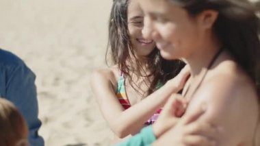 Mutlu çocukların ablasına güneş kremi sürerken yan görünümü