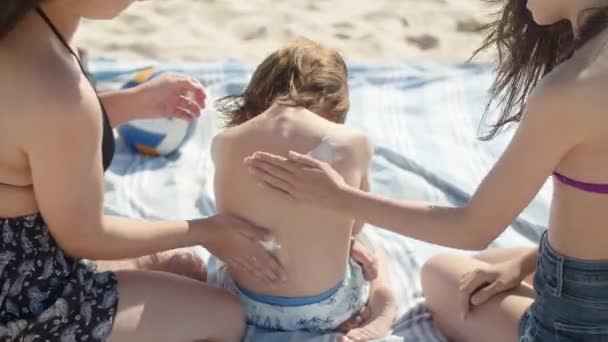 Vista posteriore di ragazze felici che applicano la protezione solare sui fratelli indietro — Video Stock