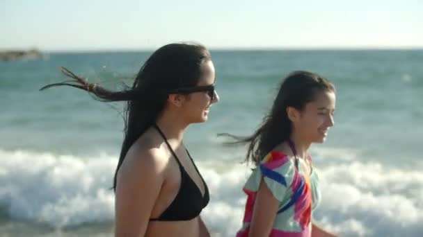 Vista laterale di ragazze adolescenti sorridenti che camminano lungo la costa — Video Stock