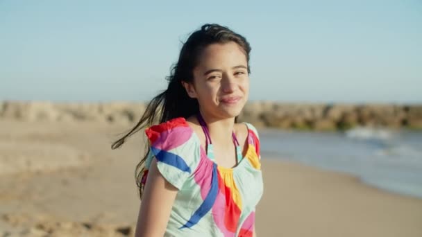 Média tiro de muito sorridente adolescente sentada na praia — Vídeo de Stock