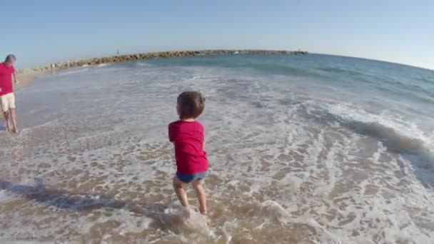 Largo tiro de niño salpicando agua en padre y hermanas en la playa — Vídeos de Stock