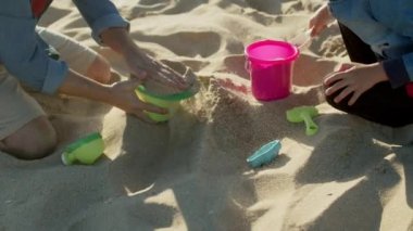 Baba ve oğlunun kumsalda kumla oynadığı orta boy bir fotoğraf.