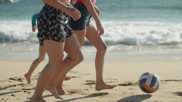 Vista lateral de los niños corriendo con pelota a lo largo de la costa — Vídeos de Stock