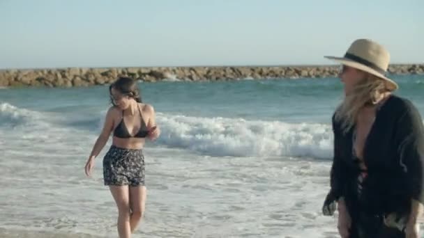 Colpo lungo di famiglia in piedi sulla spiaggia e spruzzi in mare — Video Stock