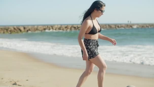 Largo tiro de chica feliz corriendo y golpeando la pelota en la playa — Vídeos de Stock
