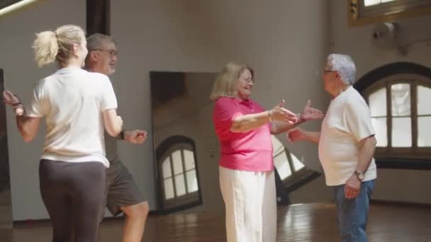Largo tiro de las parejas mayores teniendo clase de baile en el salón de baile — Vídeos de Stock