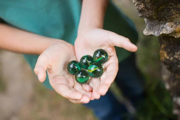 Zbliżenie zielone kulki marmuru w rękach — Zdjęcie stockowe
