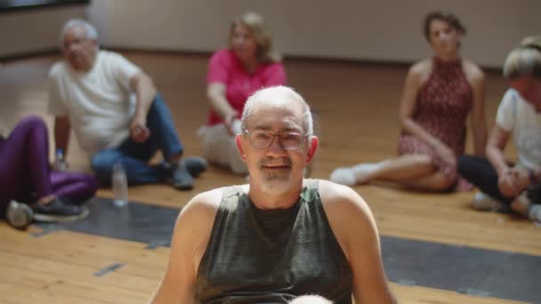 Hombre mayor sentado en el estudio de baile y mirando a la cámara — Vídeos de Stock