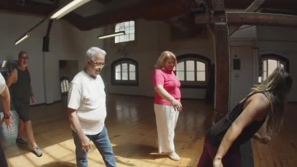 Largo tiro de personas mayores aprendiendo movimientos de baile con el maestro — Vídeos de Stock