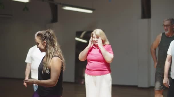 Χαρούμενη δασκάλα που δείχνει χορευτικές κινήσεις σε ηλικιωμένους — Αρχείο Βίντεο