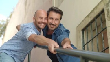 Mutlu gayler öpüşüyor ve merdivenleri tutuyorlar.