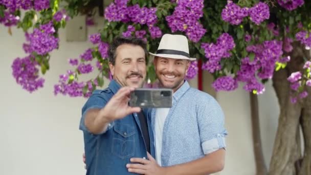 Zeitlupe eines glücklichen homosexuellen Paares beim Selfie am Telefon im Park — Stockvideo