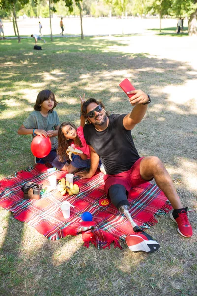 Kärleksfull pappa med funktionshinder tar selfie med barn på picknick — Stockfoto