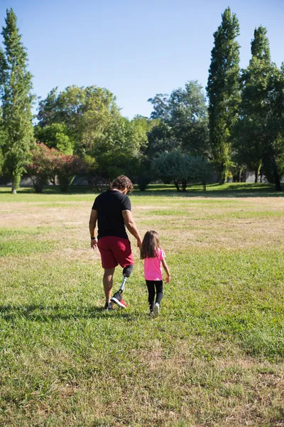 Обратно вид счастливого отца с инвалидностью ходьба с дочерью — стоковое фото