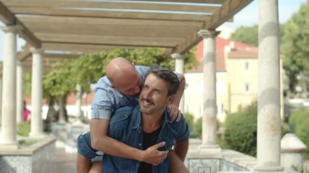 Щасливий гомосексуальний чоловік носить хлопця на спині — стокове відео