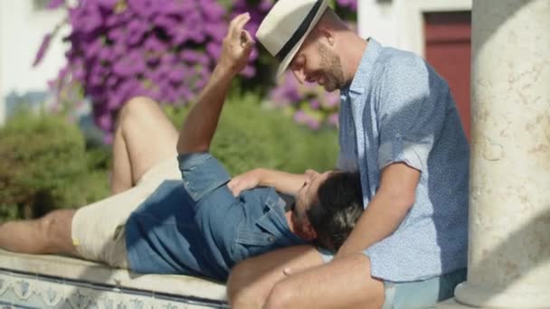 Портативный снимок гея, лежащего на коленях у своих любовников в саду — стоковое видео
