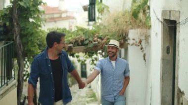 Neşeli gay erkek arkadaşının elini tutuyor ve merdivenleri tırmanıyor.