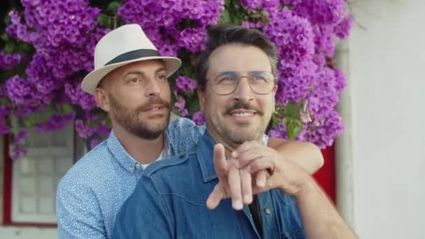 Tembakan menengah gay bahagia berdiri dan berpelukan di kebun musim panas — Stok Video