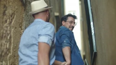 Evlerin arasında yürüyen mutlu erkek eşcinsel çift.