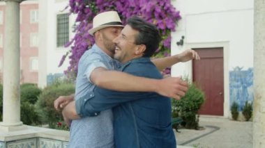 Neşeli sakallı eşcinsel adam erkek arkadaşına sıkıca sarılıyor.