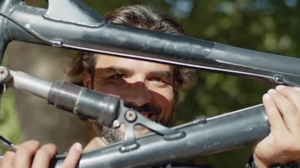 Zbliżenie strzał z szczęśliwy człowiek patrząc w aparat rzut rower — Wideo stockowe