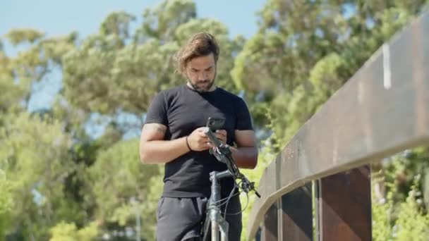 Parkta bisiklet sürerken telefon kullanan ciddi atletlerin ön görüntüsü — Stok video