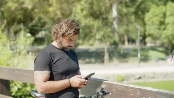 Rowerzysta rozmawiający przez telefon z przyjaciółmi podczas jazdy na rowerze — Wideo stockowe