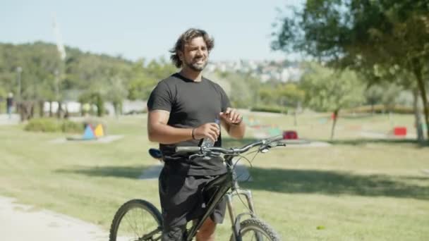 Κουρασμένος άνθρωπος με τεχνητό πόδι πόσιμο νερό κατά τη διάρκεια της ποδηλασίας — Αρχείο Βίντεο