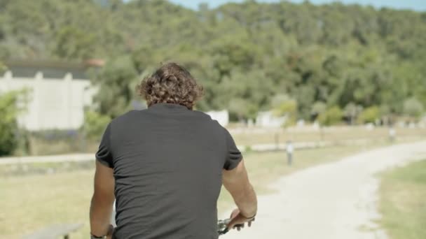 Вид сзади человека в спортивной одежде на велосипеде на открытом воздухе — стоковое видео